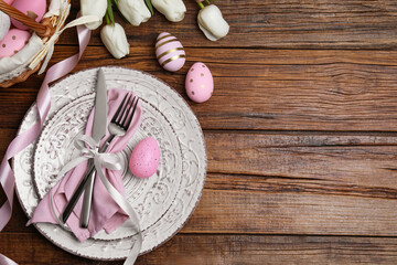 Festive table setting with painted eggs and tulips, flat lay with space for text. Easter celebration