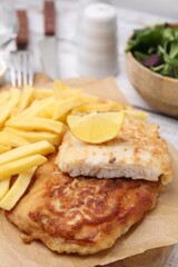 Tasty soda water battered fish, potato chips and lemon slice on table, closeup