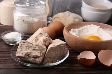 Compressed yeast, flour, salt, dough and eggs on wooden table