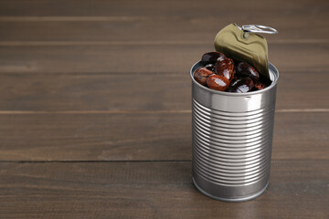 Tin can with kidney beans on wooden table, space for text