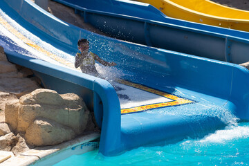 Child on water slide at aquapark. Summer holiday.