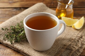 Aromatic herbal tea with thyme on wooden table, closeup