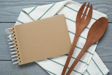Blank recipe book and kitchen utensils on grey wooden table, flat lay. Space for text