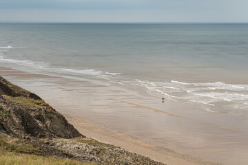 Couple (unrecognisable) walking on a large sandy Beach in North Norfolk, England