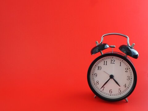 alarma reloj despertador retro negro aislado sobre fondo rojo a la derecha con espacio para texto