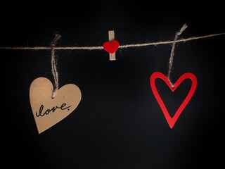composición para enamorados de tarjeta con corazones colgados en una cuerda sobre fondo negro. La...