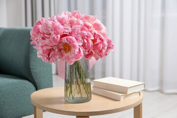 Beautiful bouquet of pink peonies in vase and books on wooden table indoors - Powered by Adobe