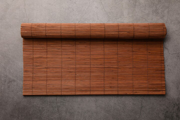 Rolled bamboo mat on grey table, top view. Space for text