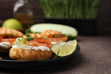 Delicious profiteroles with cream cheese, salmon and cucumber on textured table, closeup. Space for text