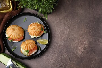 Delicious profiteroles and ingredients on textured table, flat lay. Space for text