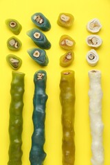 Many different delicious churchkhelas on yellow background, flat lay