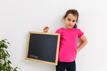 Smiling Little School Girl Holding Blank Chalk Board with Copy Space