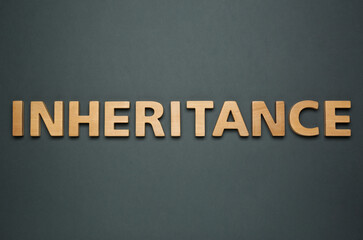 Word Inheritance made with wooden letters on black background, flat lay