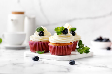 Cupcakes, muffins decorated with cream, berries and green mint leaves. Delicious homemade dessert. Pastry.