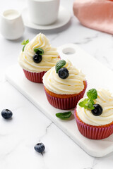 Cupcakes, muffins decorated with cream, berries and green mint leaves. Delicious homemade dessert. Pastry.