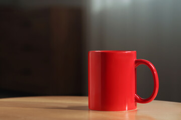 Red mug on wooden table indoors. Mockup for design