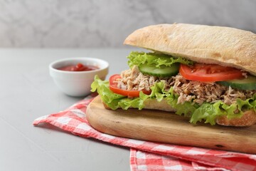 Delicious sandwich with tuna, vegetables and tomato sauce on light grey table, closeup. Space for text