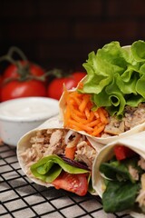 Delicious tortilla wraps with tuna on grill grate, closeup. Space for text