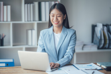 Asian businesswoman talking on phone, using laptop, looking at screen, entrepreneur manager...