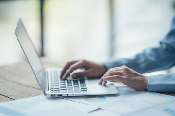 Asian businesswoman talking on phone, using laptop, looking at screen, entrepreneur manager consulting client by call, looking at computer screen, discussing