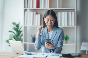 Asian businesswoman talking on phone, using laptop, looking at screen, entrepreneur manager consulting client by call, looking at computer screen, discussing