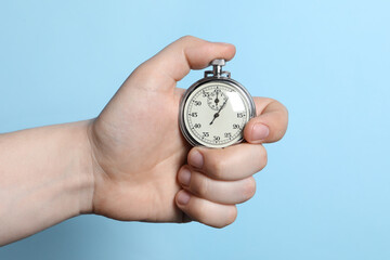 Man holding vintage timer on light blue background, closeup