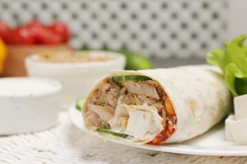 Delicious tortilla wrap with tuna on white wicker mat, closeup. Space for text