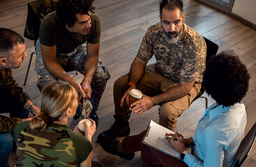 Group of diverse veterans talking during PTSD support group. - obrazy, fototapety, plakaty