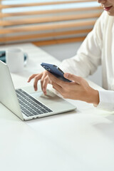Fototapeta premium Cropped shot young businessman in white shirt texting messages, chatting in social on smartphone