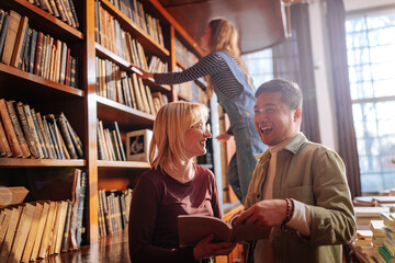 Joyful students browsing books in library.