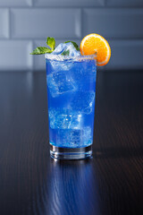 Blue lemonade with ice and decoration of mint and mandarin slices. Side view, selective focus.