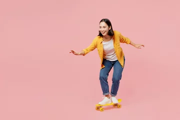 Tischdecke Full body young happy fun cool woman of Asian ethnicity wear yellow shirt white t-shirt riding skateboard pennyboard isolated on plain pastel light pink background studio portrait. Lifestyle concept. © ViDi Studio