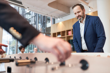 Business man playing table football with a colleague