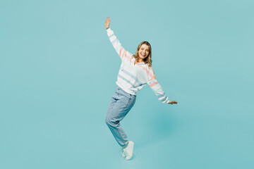 Fototapeta na wymiar Full body cheerful fun young woman wear striped hoody stand on toes leaning back with outstretched hands dance isolated on plain pastel light blue cyan background studio portrait. Lifestyle concept.