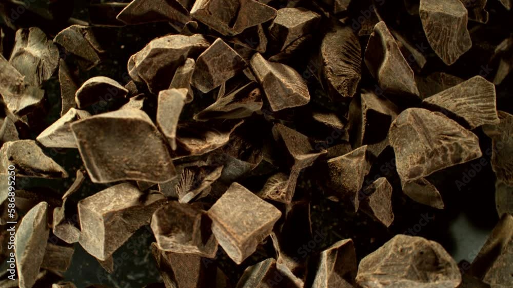 Poster super slow motion of rotating group of raw chocolate pieces. super fast camera motion. filmed on hig