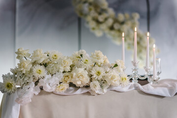 Wedding setup detail. Table setting, serving closeup. Banquet decoration in hall restaurant. Luxury reception. Festive table covered tablecloth, decorated composition flowers and candles in party area