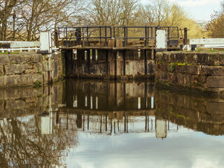 The old wooden lock gates at Hirst Wood reflected in the still waters of the Leeds and Liverpool Canal
