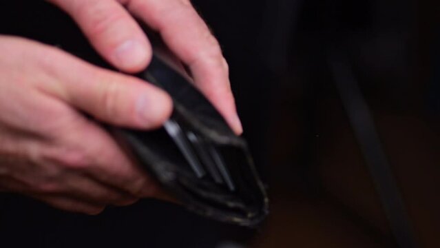 A man pulls out of his wallet and counts money in euros. View of the man's hands.