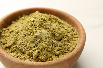 Bowl of henna powder on white marble table, closeup