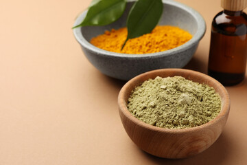 Bottle, henna and turmeric powder on coral background, space for text. Natural hair coloring