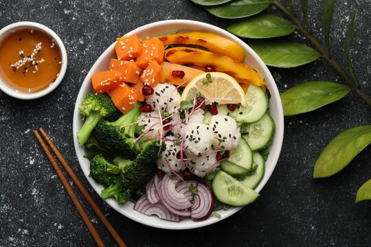 Bowl with many different vegetables and rice on grey textured table, flat lay. Vegan diet