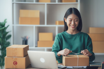 Obraz na płótnie Canvas Startup small business entrepreneur or freelance Asian woman using a laptop with box, Young success Asian woman with her hand lift up, online marketing packaging box and delivery, SME concept.