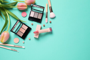 Flat lay composition with different makeup products and beautiful tulips on light turquoise...