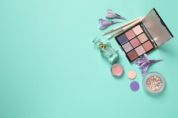 Flat lay composition with different makeup products and beautiful flowers on light turquoise background. Space for text