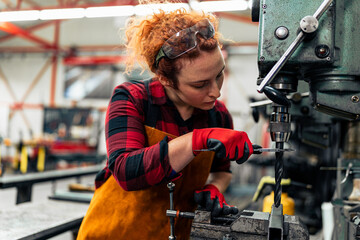 A young woman in STEM measures the diameter of a drill bit before starting work on a new project,...
