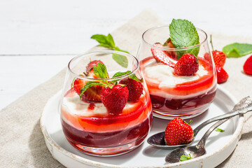 Italian dessert panna cotta in glass with strawberries. Healthy sweet food, hard light, dark shadow
