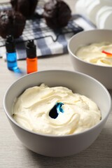 Bowls of different cream with food coloring on white wooden table
