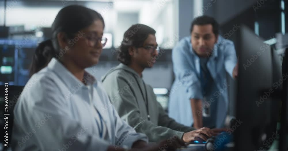 Poster Young Team of Female and Male South Asian Specialists Working on Computers and Having a Conversation at a Workplace. Two Programmers Discussing a Solution for Their New Software Upgrades