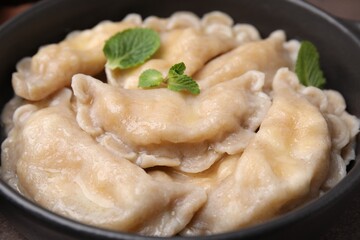 Bowl of delicious dumplings (varenyky) with cottage cheese and mint, closeup