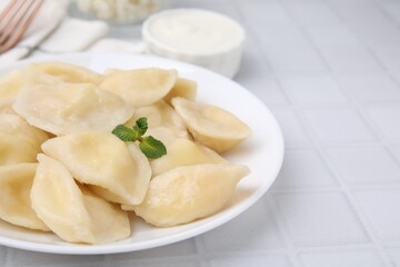Plate of delicious dumplings (varenyky) with cottage cheese on white table, closeup